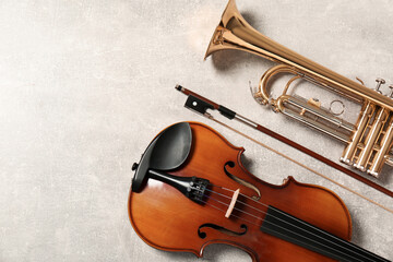 Violin and trumpet on light grey background, flat lay with space for text. Musical instruments