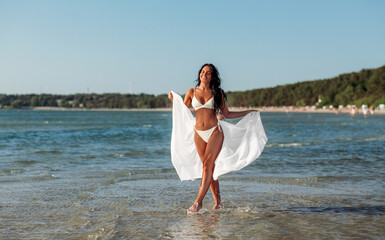 people, summer and swimwear concept - happy smiling young woman in bikini swimsuit with cover-up on...