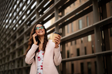Young businesswoman using the phone. Female manager talking to the phone while walking through the city.