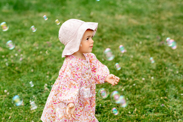 childhood, leisure and people concept - happy little baby girl playing with soap bubbles in summer