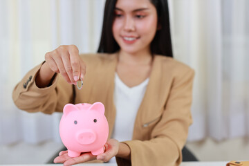 Obraz na płótnie Canvas Smart and active asian businesswoman hand putting coin into piggy bank meaning of earning money or investment or tax for business advertising concept