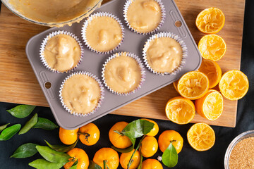 Homemade liquid dough with addition of tangerines and oranges, poured into silicone mold for making muffins, top view.