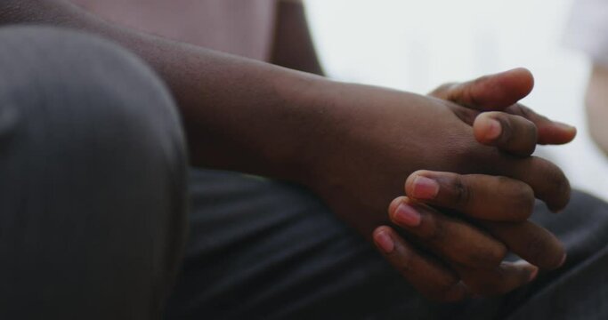 Close-up hands of an African American male who is sitting.