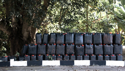 Plastic gallon. Black packaging with red cap for chemical containers is arranged outdoors. Plastic...