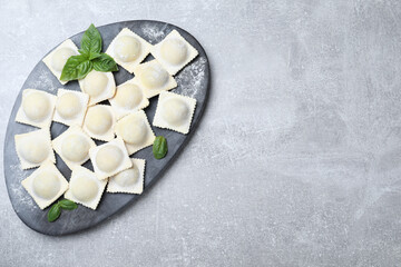 Homemade uncooked ravioli on grey table, top view. Space for text