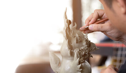 Close up of Sculptor artist creating The statue with clay. by using specific sculptural tools for drawing patterns and shaping.