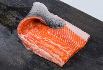 Raw trout fillet on the skin on a dark surface