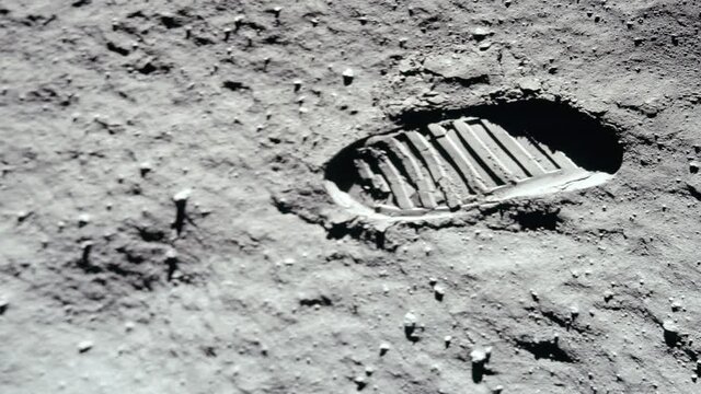 Lunar astronaut walking on the moon's surface and leaves a footprint in the lunar soil. 