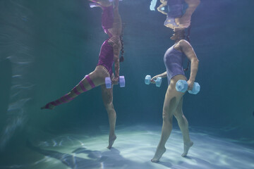 two girls go in for sports in the pool underwater on a blue background