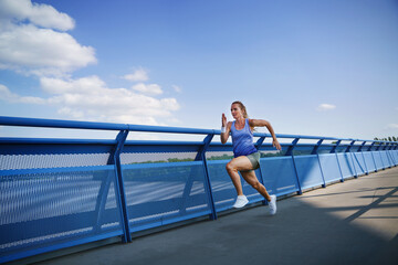 Fototapeta na wymiar Mid adult woman running outdoors in city, healthy lifestyle concept.