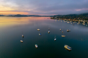 Sunrise waterscape with boats, light cloud and fog