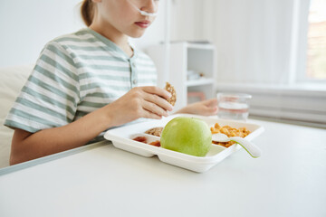 Cropped shot of girl eating healthy lunch in white hospital room, background with copy space