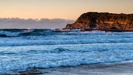 Clear skies sunrise seascape with waves and a low cloud bank on the horizon