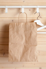A paper bag hangs near white hangers