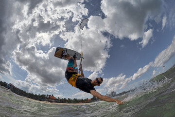 Kite surfer jumps with kiteboard in transition