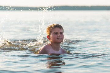 Happy smiling boy having fun swimming in the water.Cute boy swimming in water. Summer vacation.