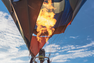 Hot flame from a gas burner light up inside of a hot air balloon at evening.
