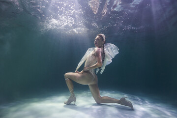 beautiful woman underwater in the sea in a beige swimsuit on a blue background