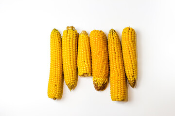 Boiled yellow sweet corn on a white background. Texture. Creative food. Swings of corn. Whole and portions of corn. Ecological food concept. Selective focus