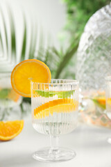 Delicious refreshing drink with orange and mint on white table