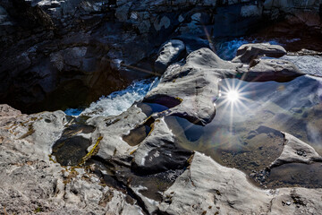 Sun reflects beautifully in the waters of a small stream of water, a wonderful lively torrent in Southern Iceland. Light diffraction star-like effect