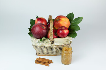 Apples in the basket with apple jam and cinnamon on the white background closeup