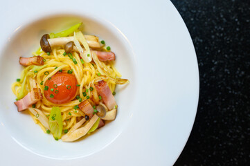 Homemade Spaghetti with yolk marinated in Japanese sauce Smoked pork belly and erinji mushrooms are placed on a white plate. isolated on black background.