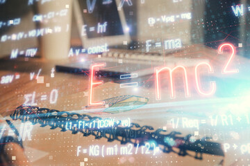 Double exposure of formula drawing and desk with open notebook background. Concept of education