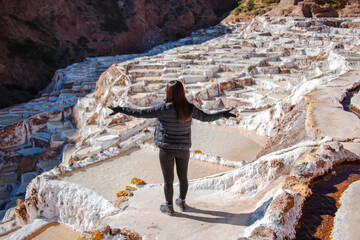 unknown woman standing with open arms in salt ponds in Maras
 - obrazy, fototapety, plakaty