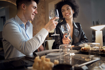 Happy Interracial couple having fun talking, eating and drinking at fusion food restaurant. Young people dating clinking wineglasses.