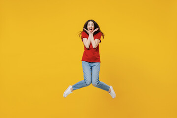Fototapeta na wymiar Full size body length shocked surprised fun young brunette woman 20s wears basic red t-shirt jump keep mouth wide open isolated on yellow background studio portrait. People emotions lifestyle concept