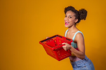Smiling afro woman holding empty shopping basket looking at camera smiling - obrazy, fototapety, plakaty