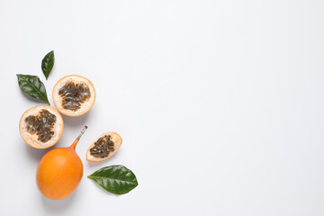 Delicious ripe granadillas with leaves on white background, flat lay. Space for text