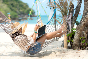 Lifestyle freelance woman using smartphone working and shopping on the beach.  Asian people smiling on hammock success and together your  in holiday. Business Summer Concept