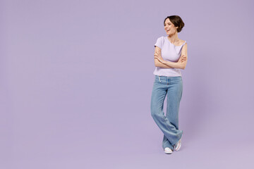 Full length young smiling happy woman 20s wear white t-shirt looking aside on workspace area hold hands crossed folded isolated on pastel purple background studio portrait. People lifestyle concept