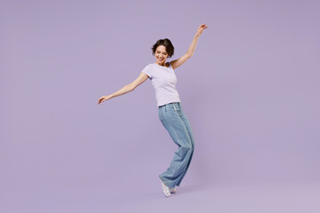 Fototapeta na wymiar Full length side view young smiling excited cheerful happy woman 20s with bob haircut in white t-shirt leaning back stand on toes dancing have fun isolated on pastel purple background studio portrait.