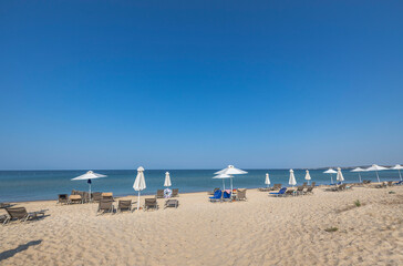 Beautiful landscape view of empty sunbeds and umbrellas on sand beach. Greece.