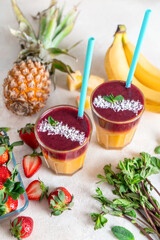 Two three-layer smoothie cocktails with fresh fruit and berry tubules. On white background