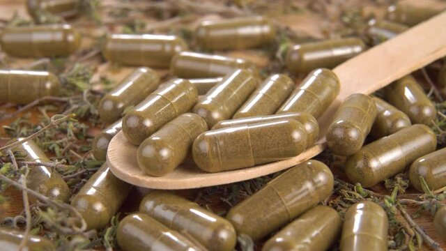 Full wooden spoon of medical herbal capsules in a pile of herbs and pills. Macro. Dolly Shot