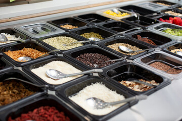 A view of a table full of ingredient bins, seen at a local acai restaurant.