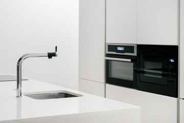 Counter with sink and faucet next to cupboard
