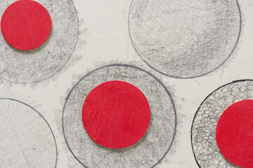 red hand painted wooden discs on pencil circles background
