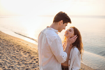 Side view tender young couple two friend family man woman in white clothes boyfriend hug girlfriend hold face going to kiss at sunrise over sea beach ocean outside seaside in summer day sunset evening