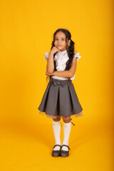 a beautiful happy dark-skinned schoolgirl girl with dark hair in a school uniform, a gray skirt and...