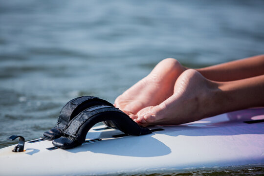 Blurred image of a paddle boarder legs, focus on black handles. Summer vacation leisure 