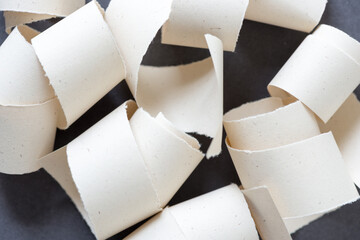 neutral paper torn and curled randomly arranged on a dark background - top-down view