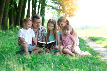 young family with children reading the Bible in nature