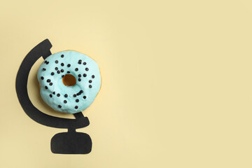 Globe made of tasty doughnut and drawing on beige background, top view. Space for text