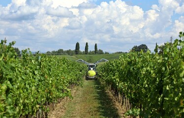 Back view of an agricultural sprayer machine trailed by a tractor sprinkling  chemical pesticides...
