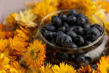 Superalimento orgánico antioxidante de arándanos, en un recipiente sobre una mesa de madera. acompañados con flores amarillas.  